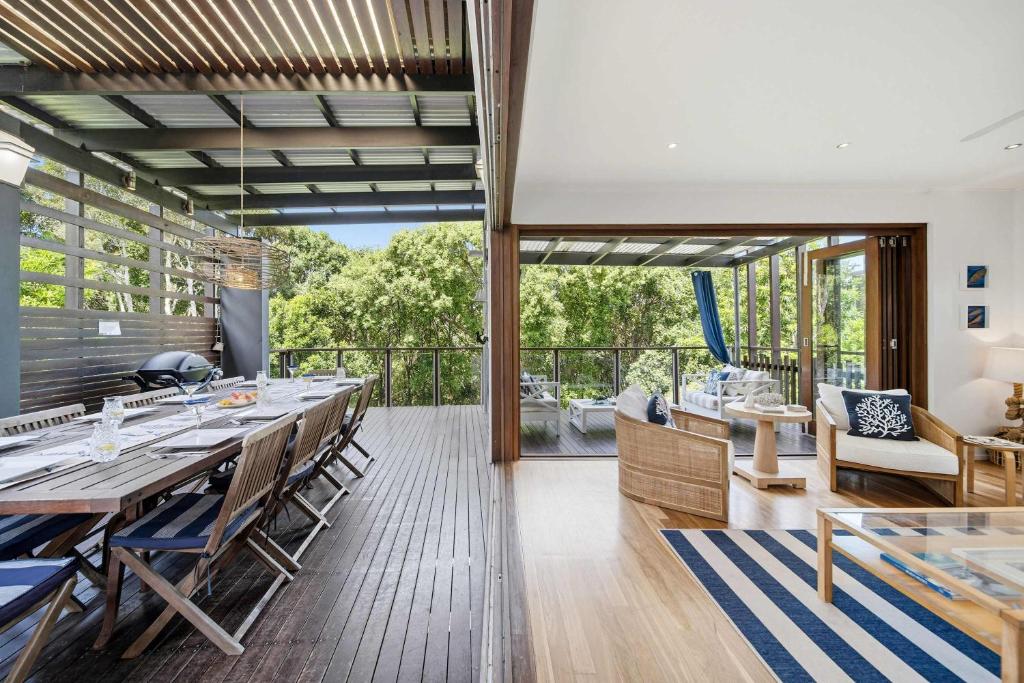 a dining room with a long table and a balcony at Family Beach House at Twin Waters Resort in Twin Waters