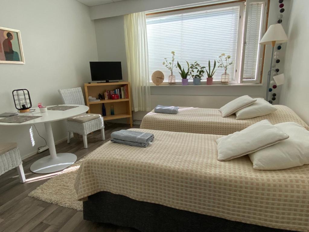 a bedroom with two beds and a table and a window at Majoitu ja nuku hyvin Hartolan keskustassa in Hartola