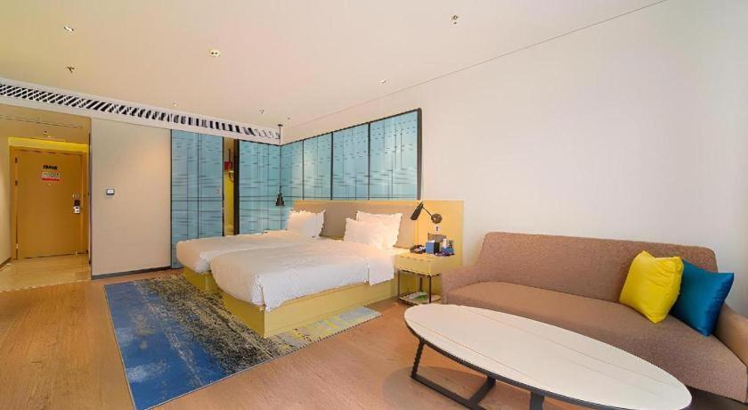a bedroom with a bed and a couch at Echarm Hotel Foshan West Station Shishan Luocun in Luocun
