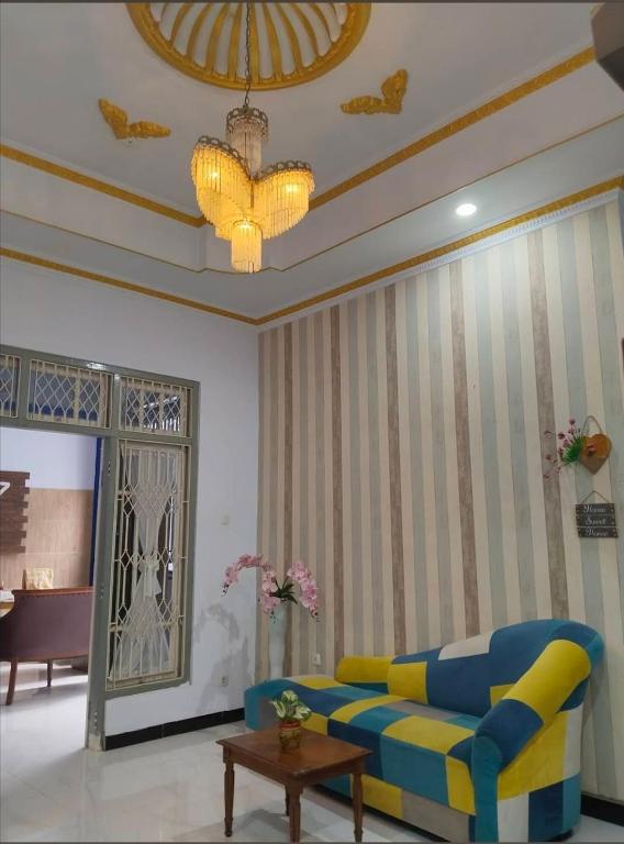 a living room with a blue couch and a chandelier at Grities 7 Home Jogja in Yogyakarta