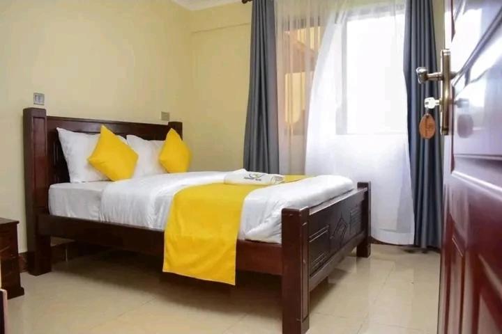 a bedroom with a bed with yellow sheets and a window at Keriwest hotel in Kericho