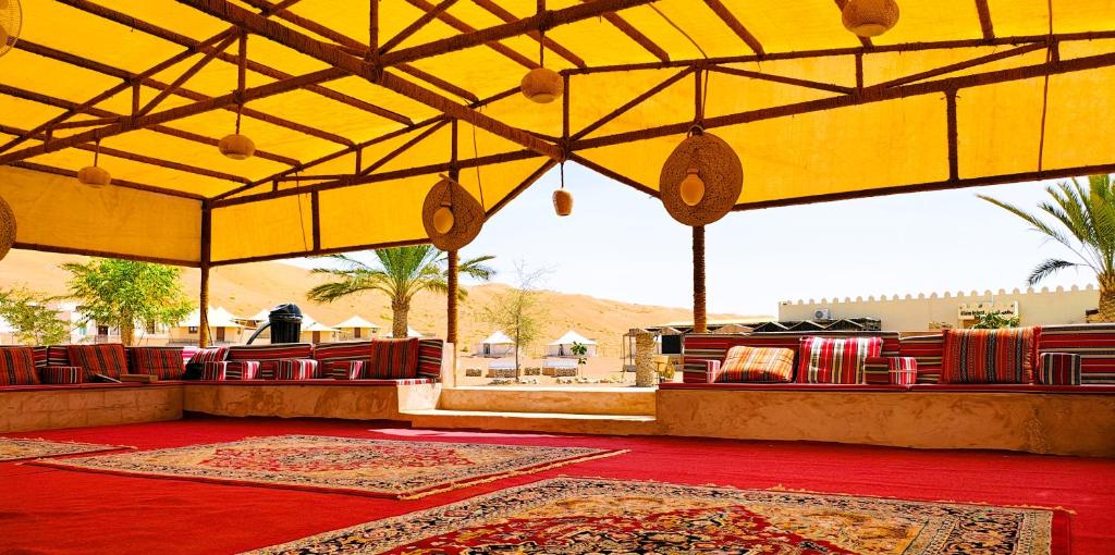 een grote kamer met tapijten op de vloer en een grote bij Al Salam Desert Camp Oman in Al Qābil