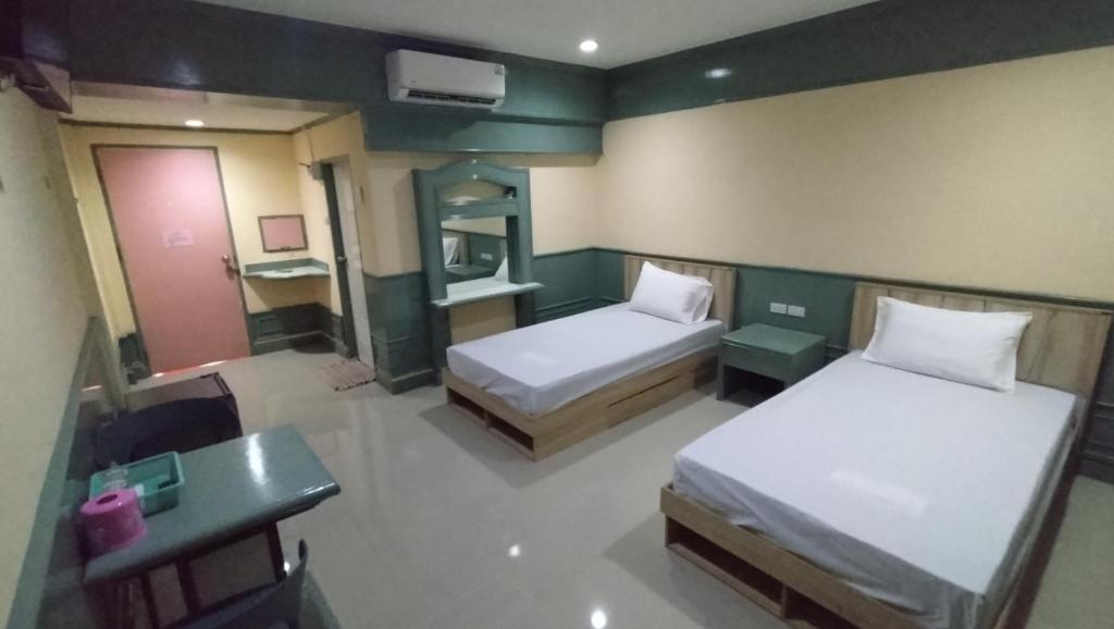 una habitación con dos camas y una mesa y un escritorio en MP Inn, en Saraburi