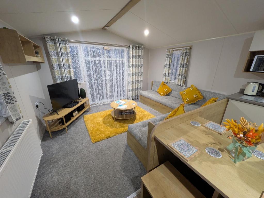 a living room with a couch and a tv at Seascape Caravan in Kinmel Bay