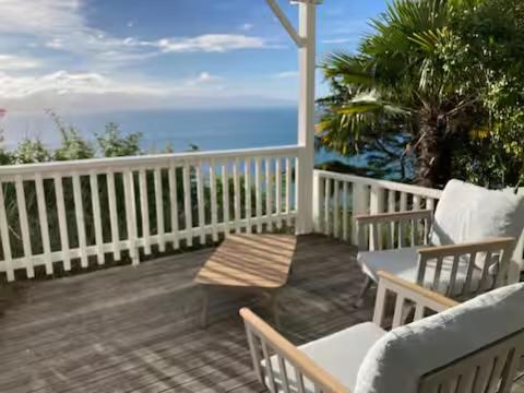 ein Balkon mit Tisch und Stühlen und dem Meer in der Unterkunft Glamping with stunning sea view in Nelson