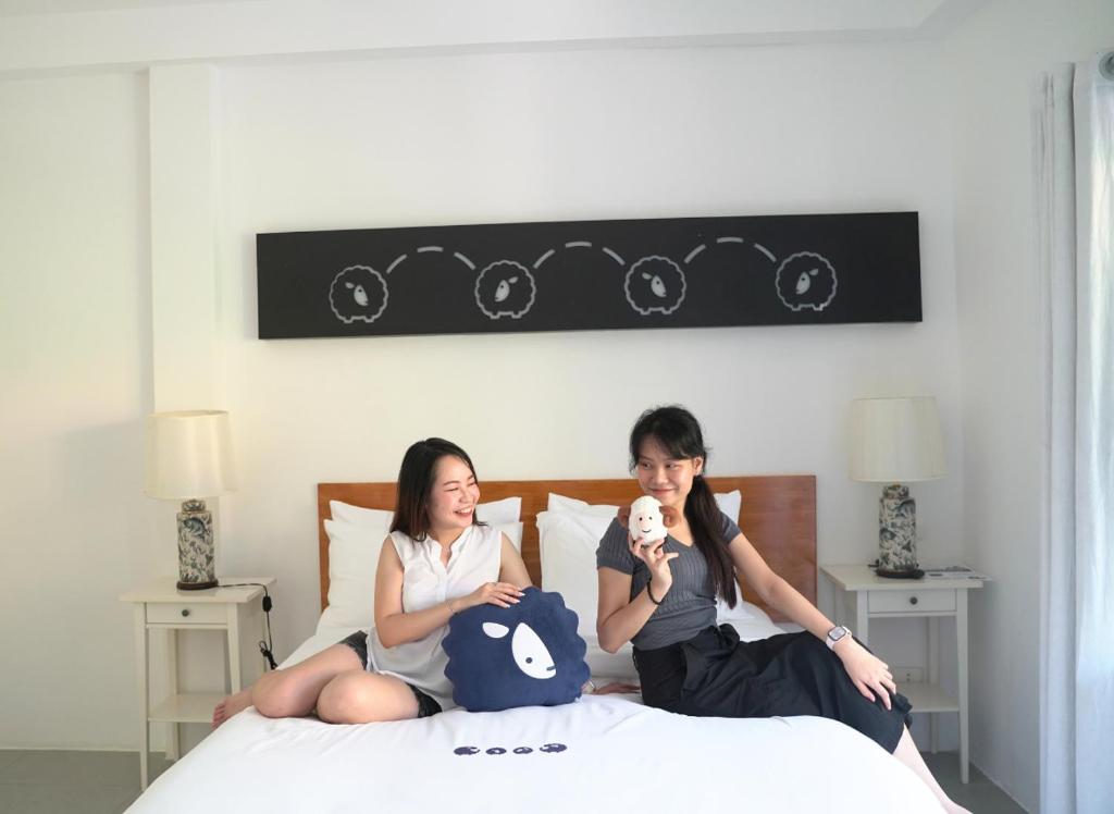 twee vrouwen zitten op een bed met een baby in hun armen bij Kokotel Khao Lak Isara Casa in Khao Lak