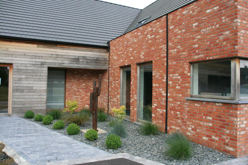 een bakstenen gebouw met planten ervoor bij La Couture du Charme in Saméon