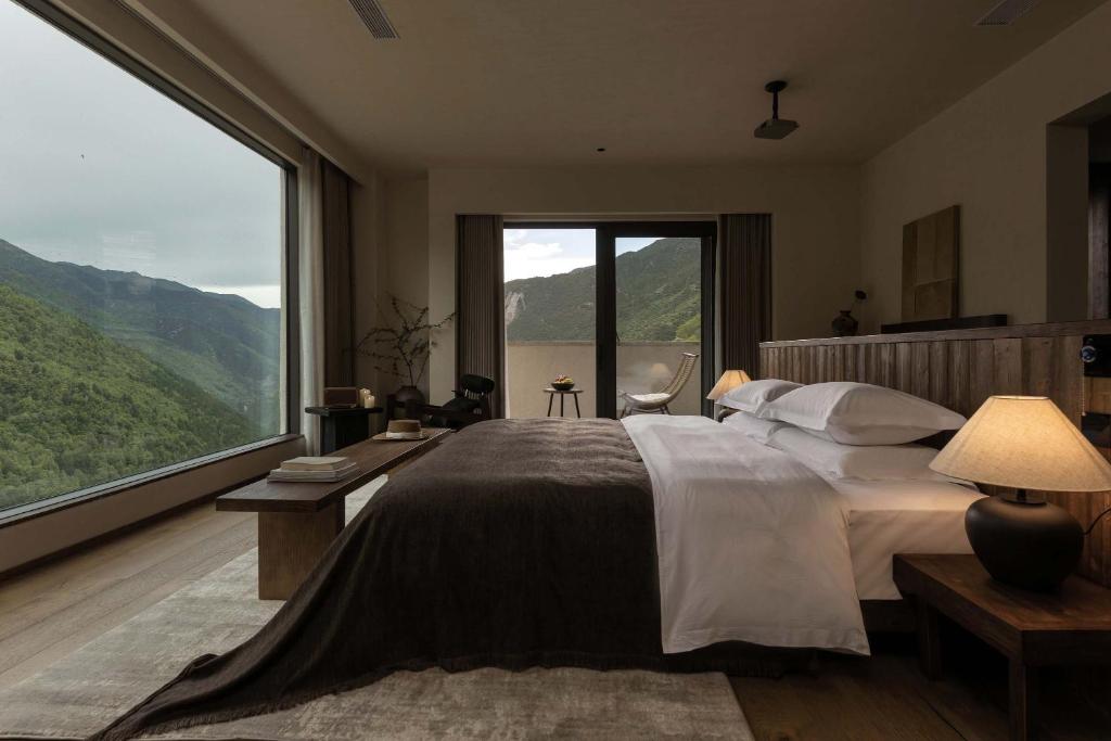 a bedroom with a large bed with a large window at Shan shang shan HOTEL in Mount Siguniang