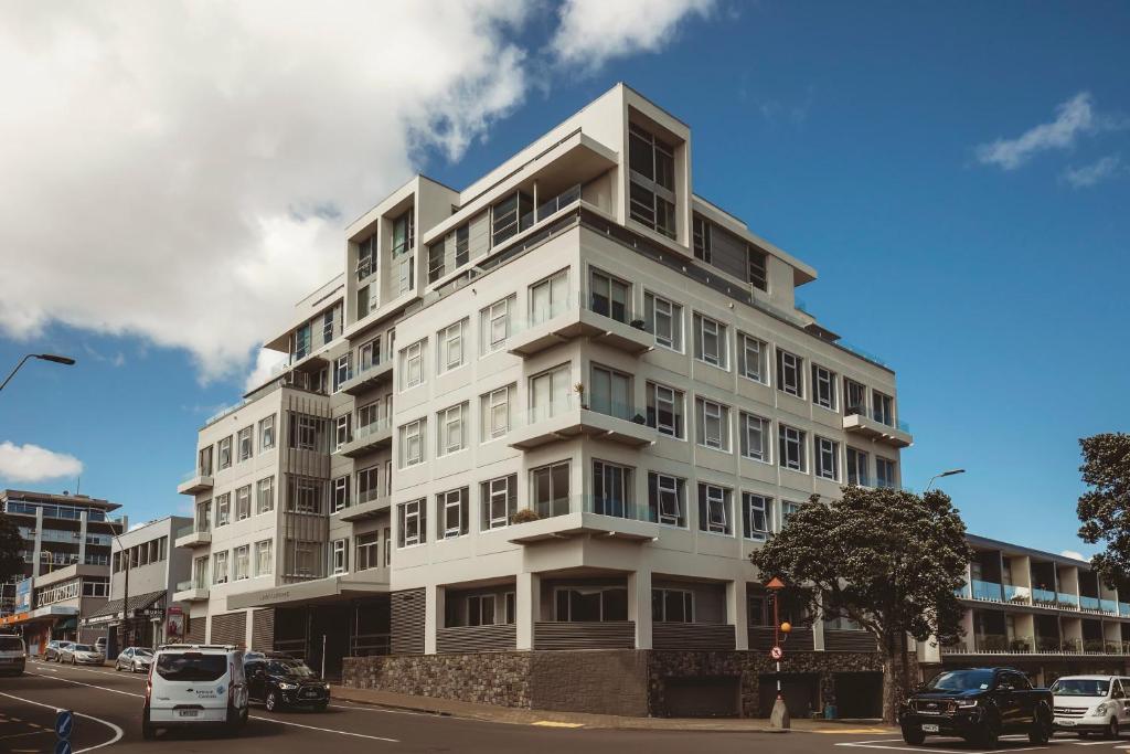 a tall white building with cars parked in front of it at Liardett Penthouse - Inner city accommodation in New Plymouth