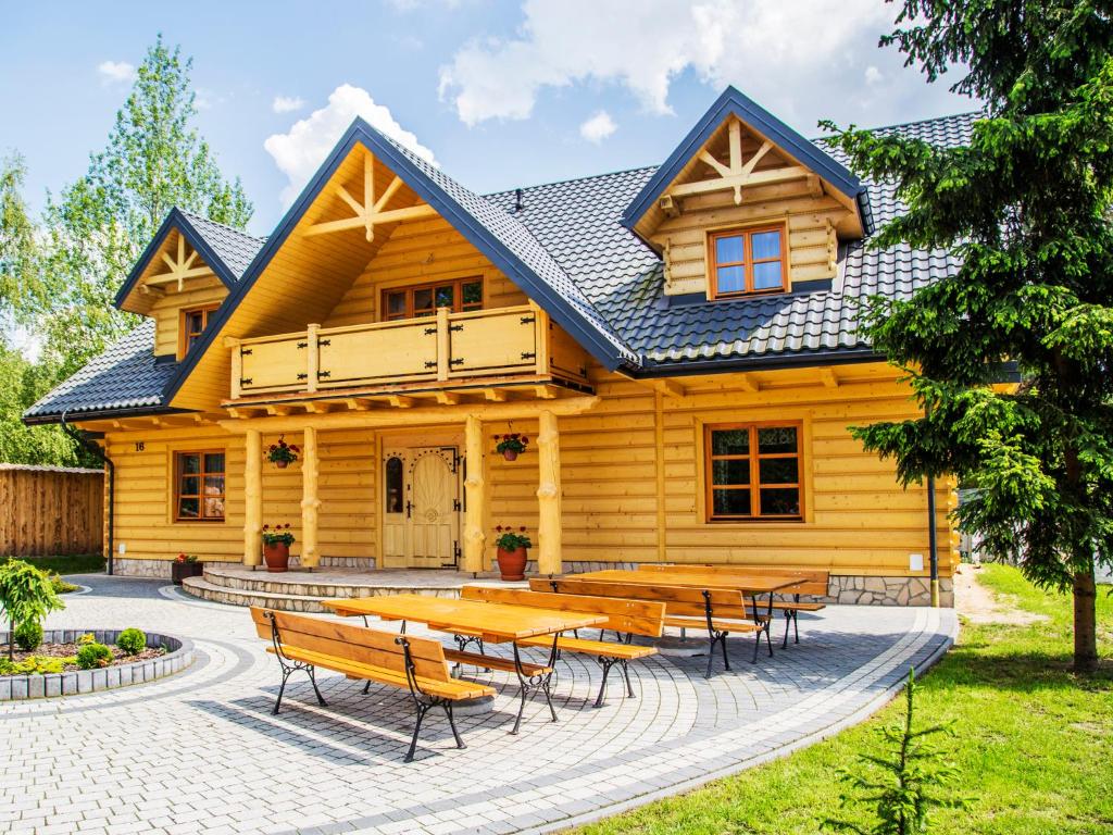 Agroturystyka Olszynka في Skopanie: منزل خشبي أمامه طاولات وكراسي