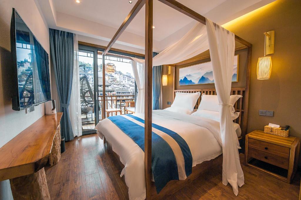 a bedroom with a canopy bed and a balcony at Fenghuang Sulv Yunzhu River View Homestay in Fenghuang