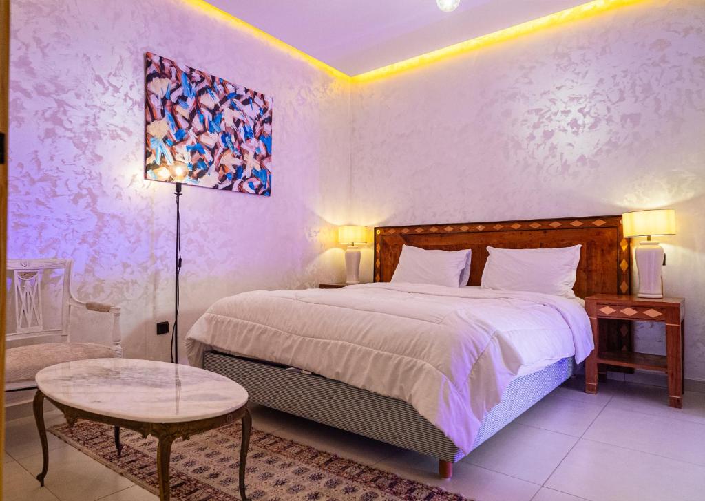 Un dormitorio con una cama, una lámpara y una mesa. en URBAN WHITE Elya 1, en Beni Mellal