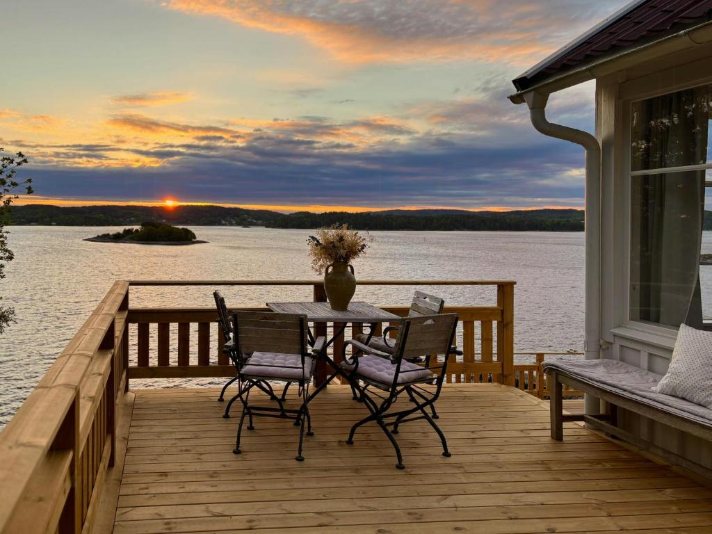 a table and chairs on a deck with a view of the water at Romantic Summer House On Orust in Stillingsön