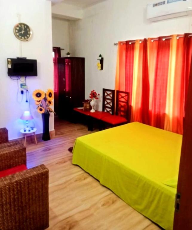a bedroom with a yellow bed and red curtains at Hotel Baruah Tower in Tezpur