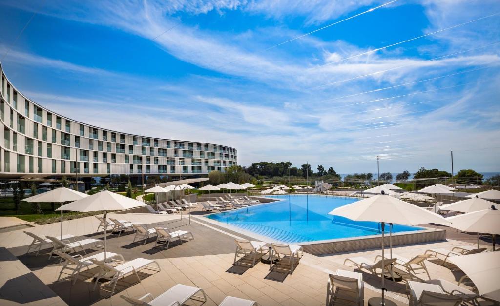 um hotel com piscina, cadeiras e guarda-sóis em Maistra Select Family Hotel Amarin em Rovinj