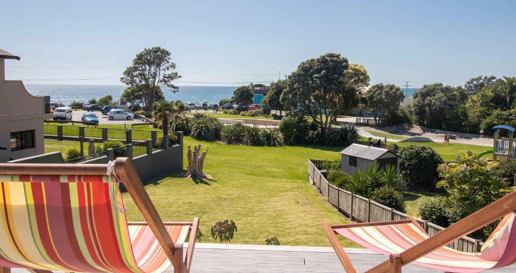 a couple of chairs sitting on a deck looking at a park at Aqua Vista On Arden - beachfront bach in Oakura in Oakura