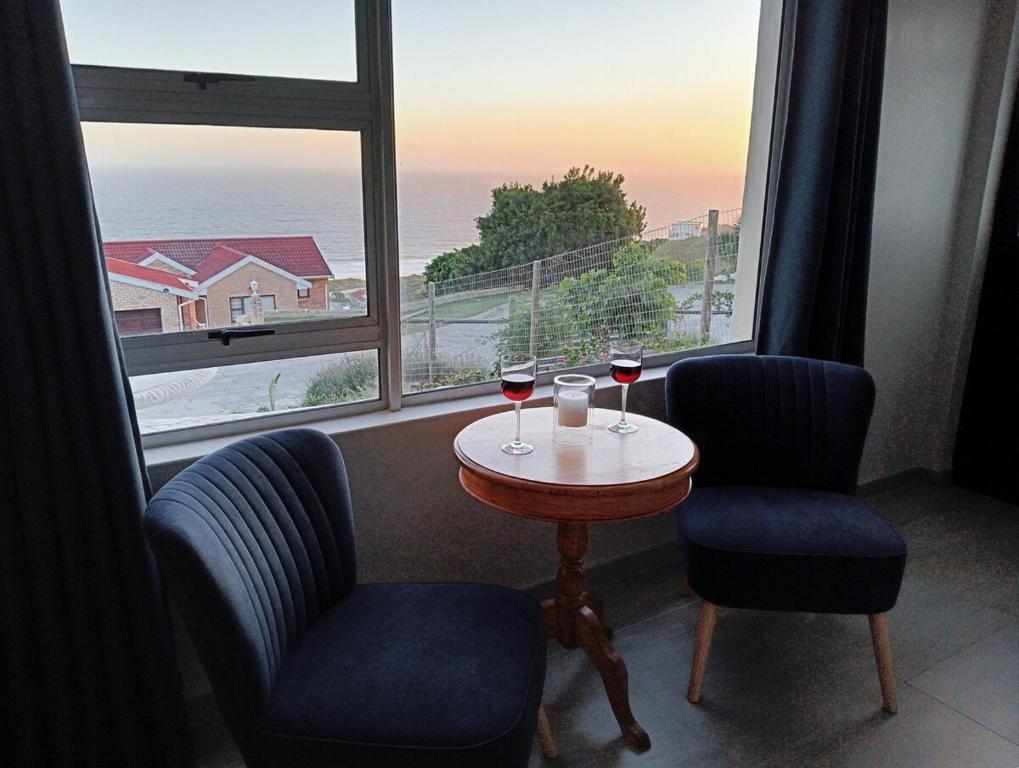 two glasses of wine sitting on a table in front of a window at See n Bos in Gqeberha