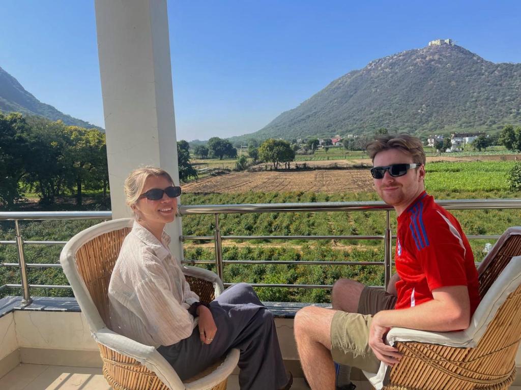 een man en een vrouw zitten op stoelen op een veranda bij Hotel Divine Palace Pushkar in Pushkar