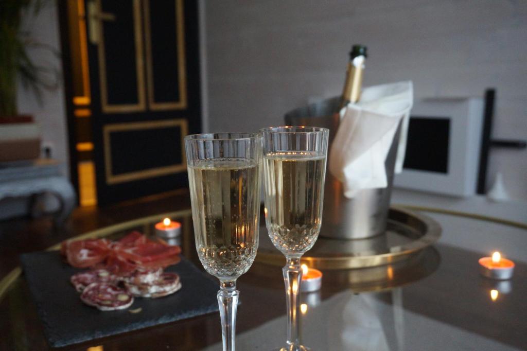 two glasses of champagne on a table with candles at Glamour Jacuzzi Privé Chambéry in Chambéry