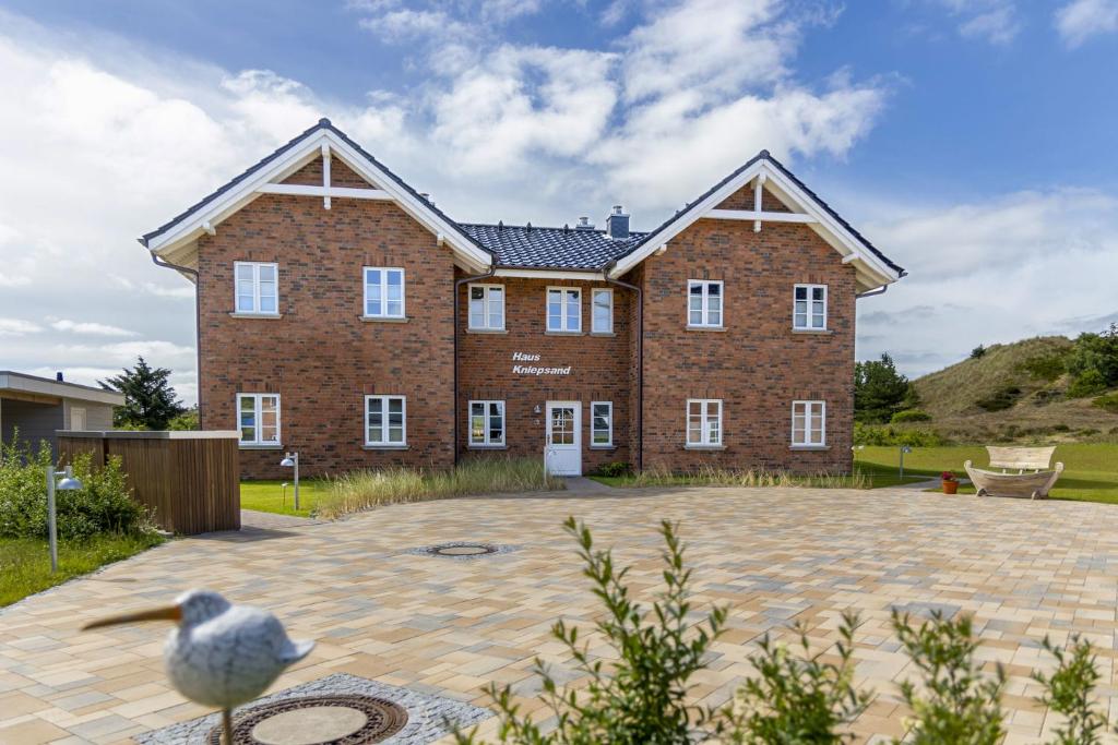una grande casa di mattoni con un uccello davanti di Haus Kniepsand, Wohnung Treibsand a Wittdün