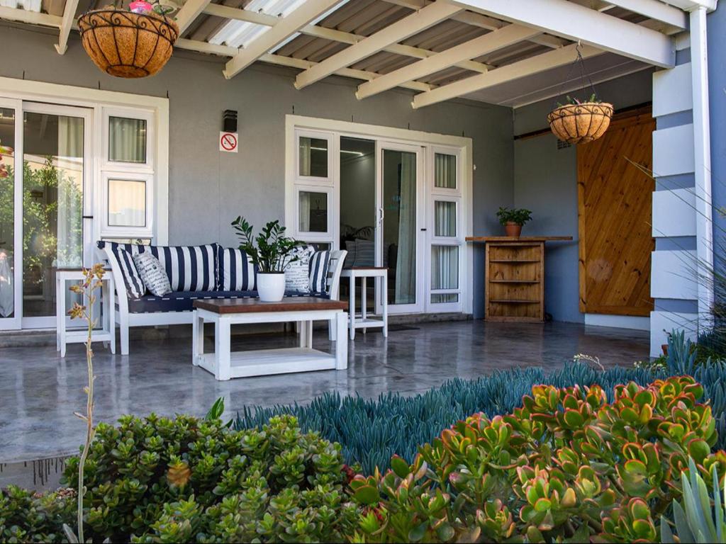 een veranda met stoelen en een tafel op een huis bij La Dolce Vita Gordon’s Bay in Gordonsbaai