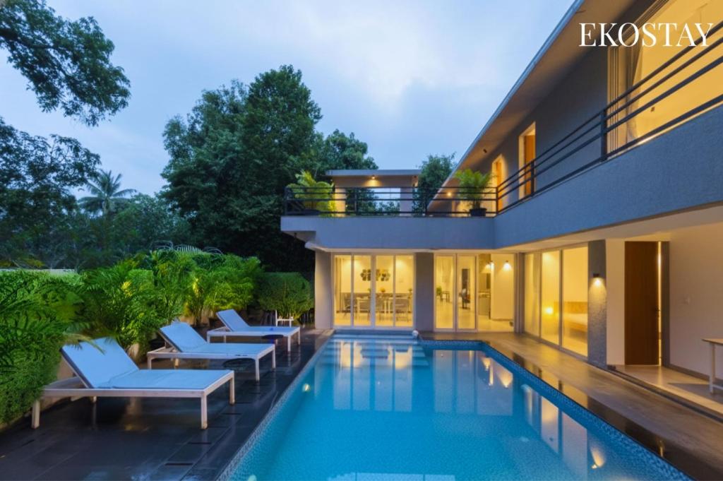 a swimming pool with lounge chairs and a building at EKOSTAY Gold - AshBee Villa in Kīhīm