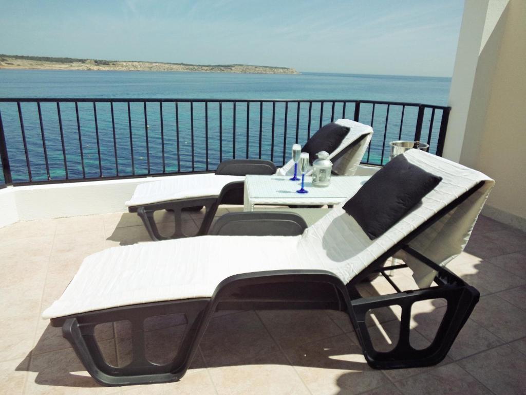 a balcony with a table and chairs and the ocean at Seafront apartment 2 bedrooms Terrace & Panoramic ocean views in Is-Sellum