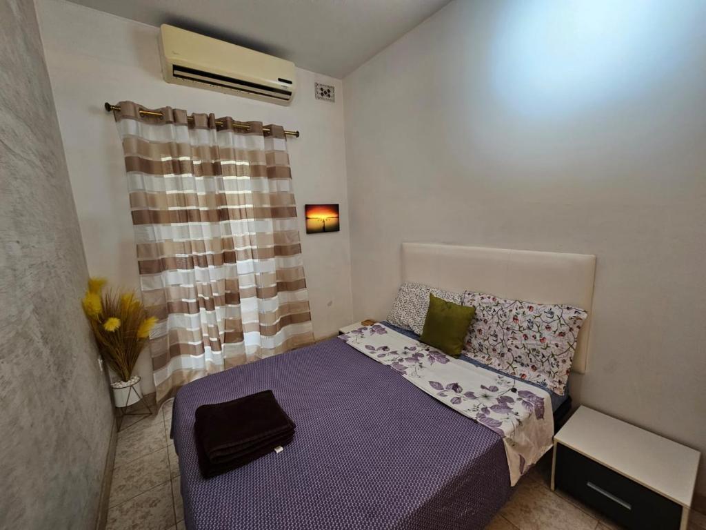 Un pequeño dormitorio con una cama morada y una ventana en Elegant Oceanfront Apartment with Coastal Charm S11, en Sliema