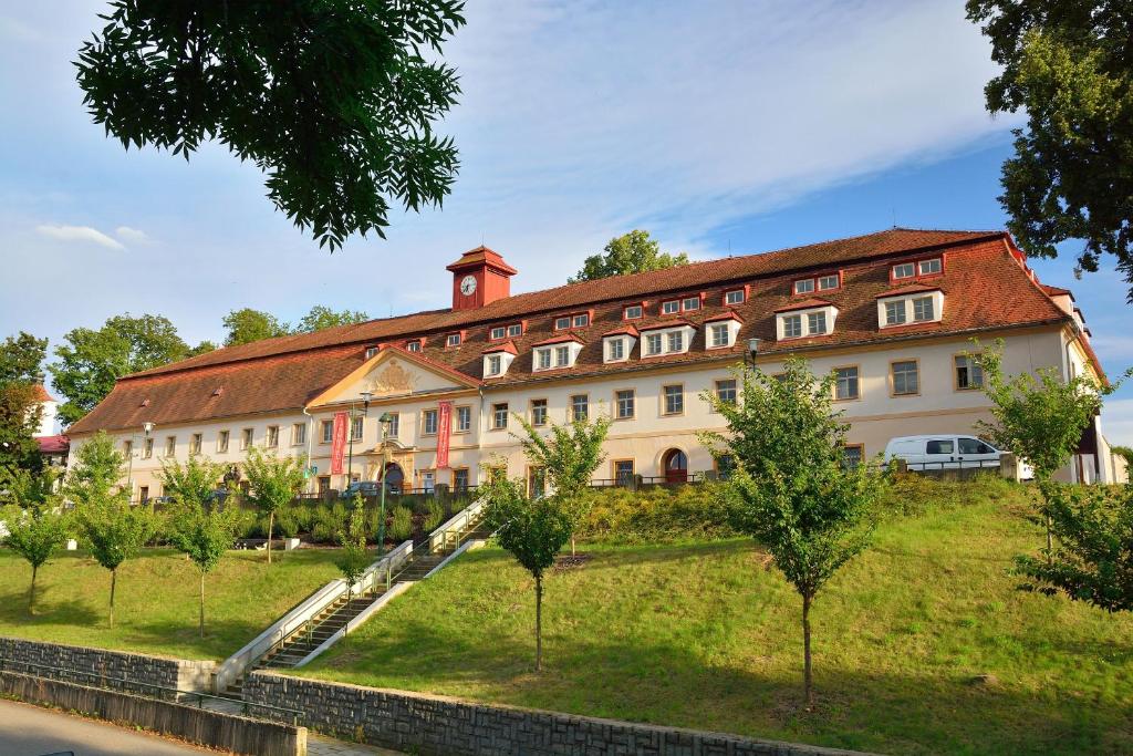 a large building on a hill with trees in front at Hotel Tynec in Týnec nad Sázavou