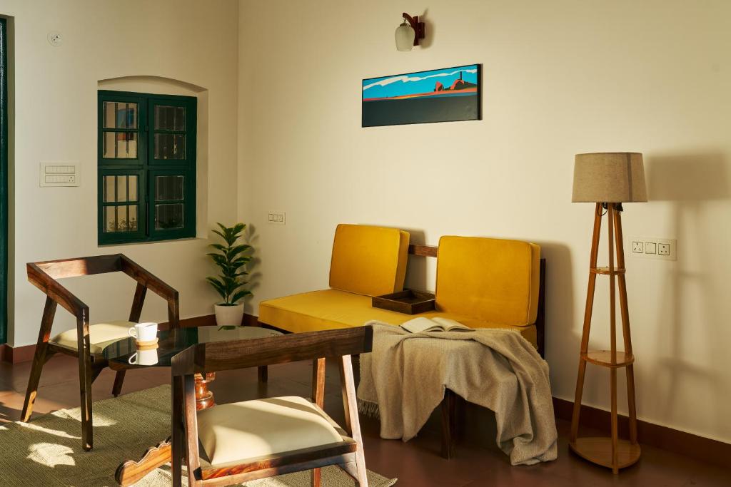 a living room with two chairs and a table at Notu by Raho - Secluded Villa with Estate View in Siddapur