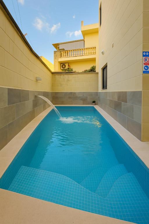 a swimming pool with a fountain in a house at The Allure - GV in Nadur