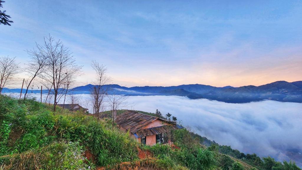 a house on top of a hill in the clouds at A Su Homestay Mù Cang Chải in Mù Cang Chải