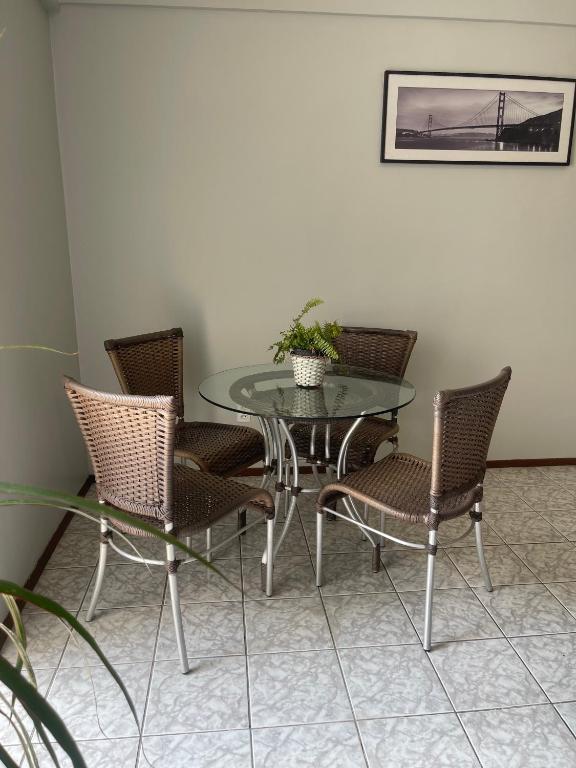 a glass table and chairs with a potted plant on it at Apartamento aconchegante in Belém