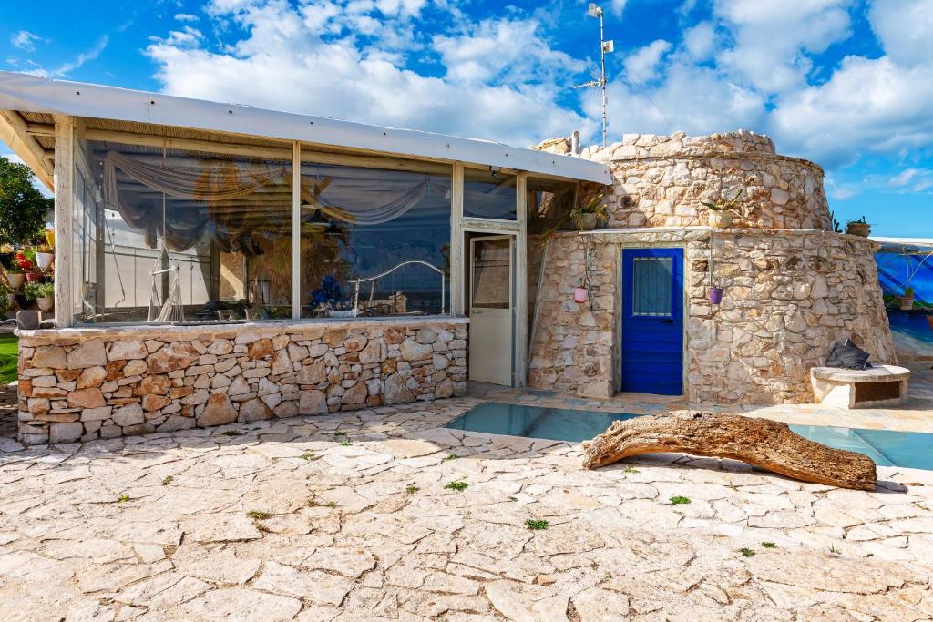 une maison en pierre avec une porte bleue et une fenêtre dans l'établissement Il Trullo al Mare -Trullo by the sea- Pool & Beach, à Molfetta
