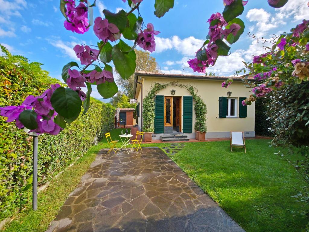 a garden with a house with purple flowers at Villetta Tonfano in Marina di Pietrasanta