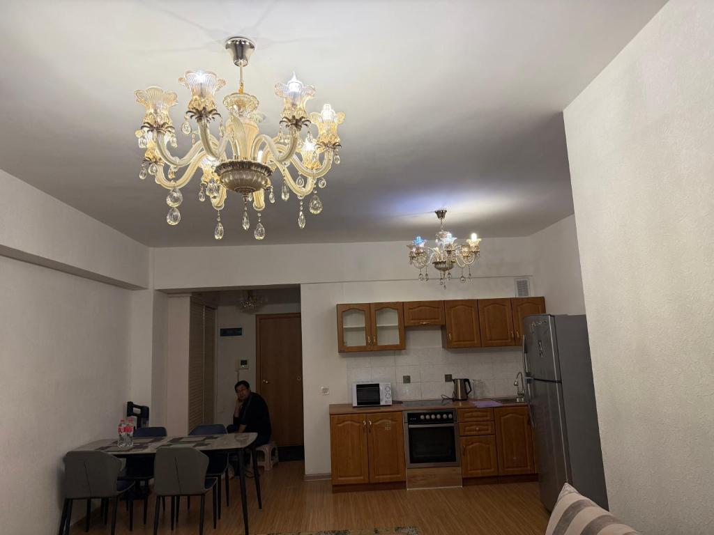 Ein Mann sitzt an einem Küchentisch unter einem Kronleuchter. in der Unterkunft Enereltsogtsolbor in Ulaanbaatar