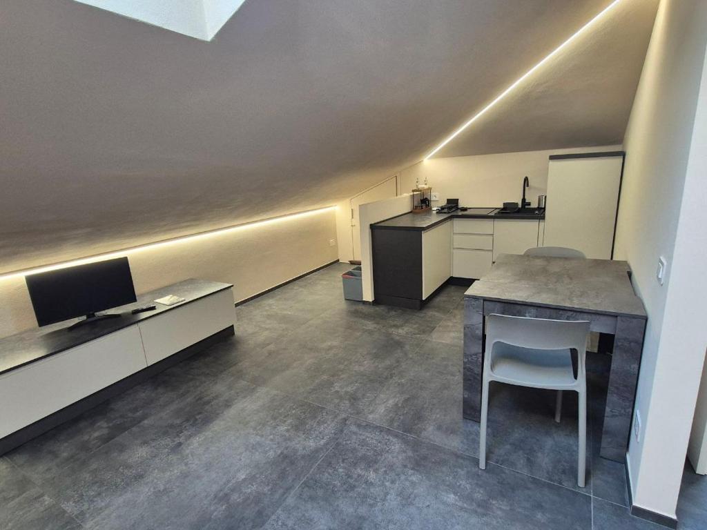 a room with a kitchen with a table and a tv at Moderna Mansarda con parcheggio gratuito in Diano dʼAlba