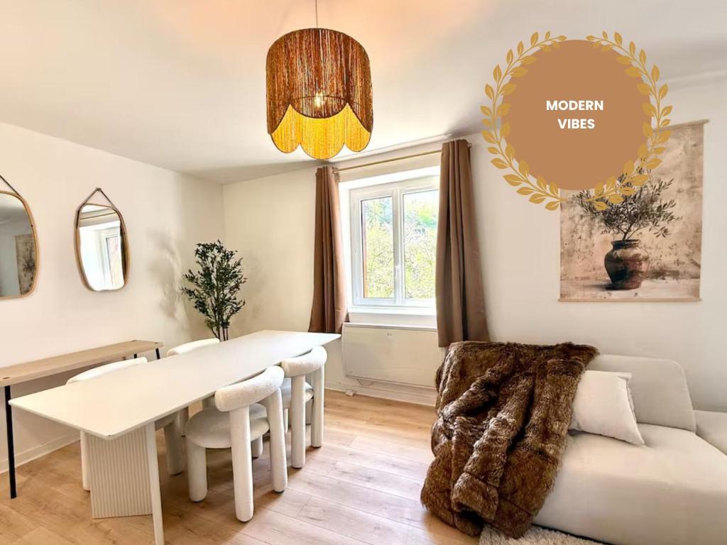 a dining room with a white table and a couch at Cocon lumineux - direct Geneva - Gare Bellegarde in Bellegarde-sur-Valserine