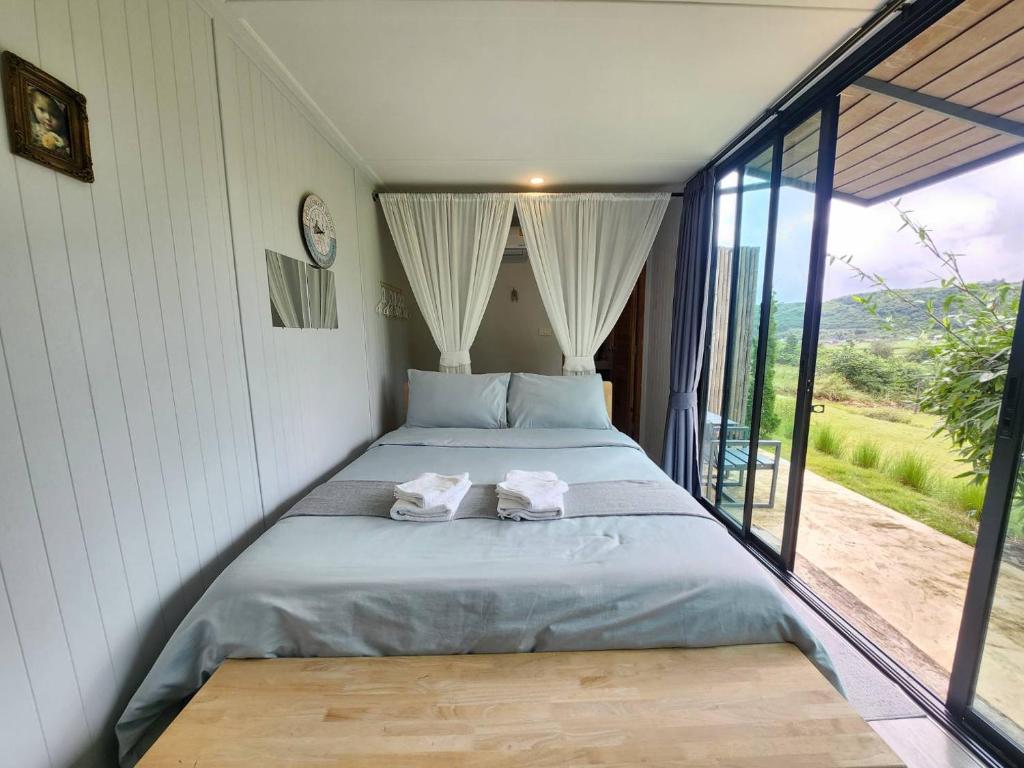 a bed in a room with a large window at the cabin hulk เขาใหญ่ in Ban Nong Song Hong
