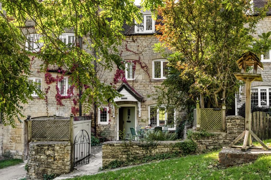 a stone house with a gate and a fence at 4 Court Cottages in Blockley