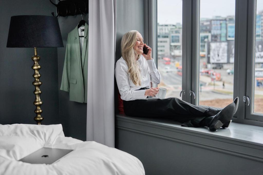 a woman sitting on a window sill talking on a cell phone at Hotel Filip in Oslo