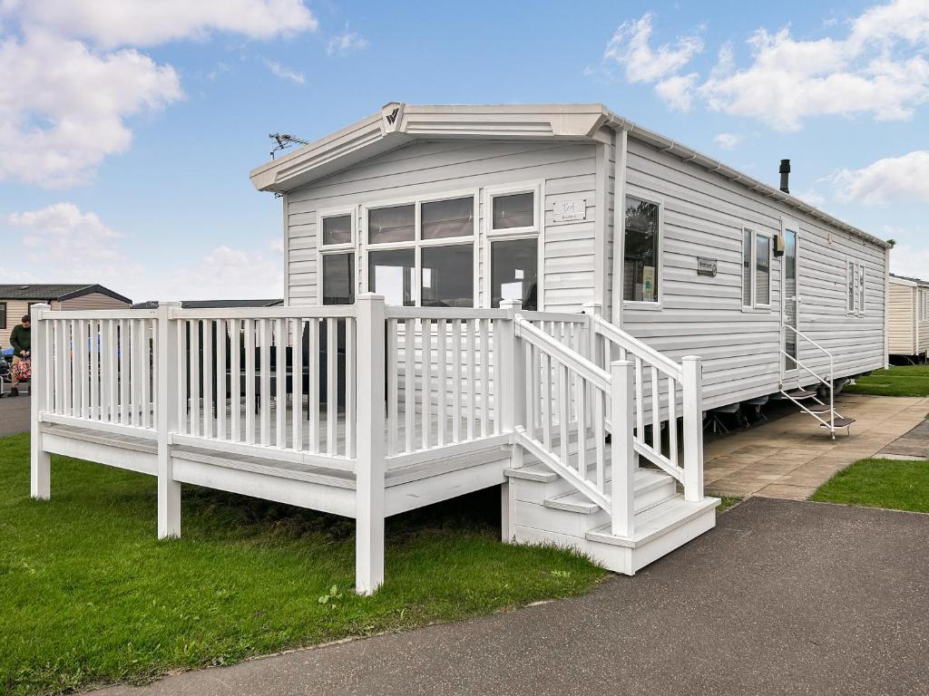 a white tiny house with a white porch at Coastal Bay View in Ayr