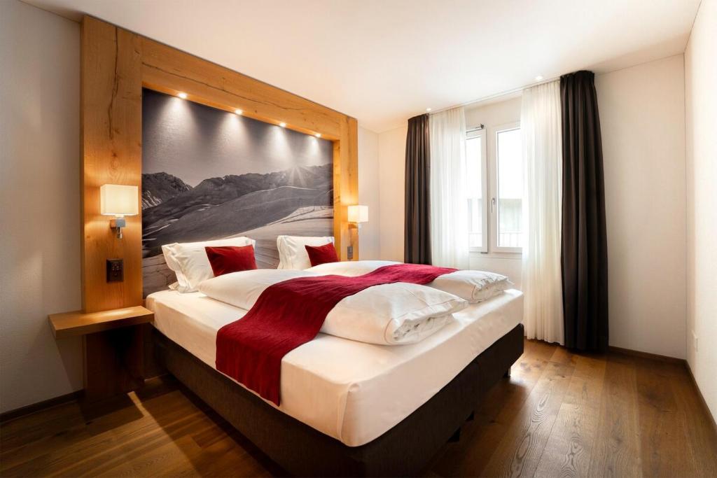 een slaapkamer met een groot bed met een groot schilderij aan de muur bij Apartment Crown Andermatt-6 in Andermatt