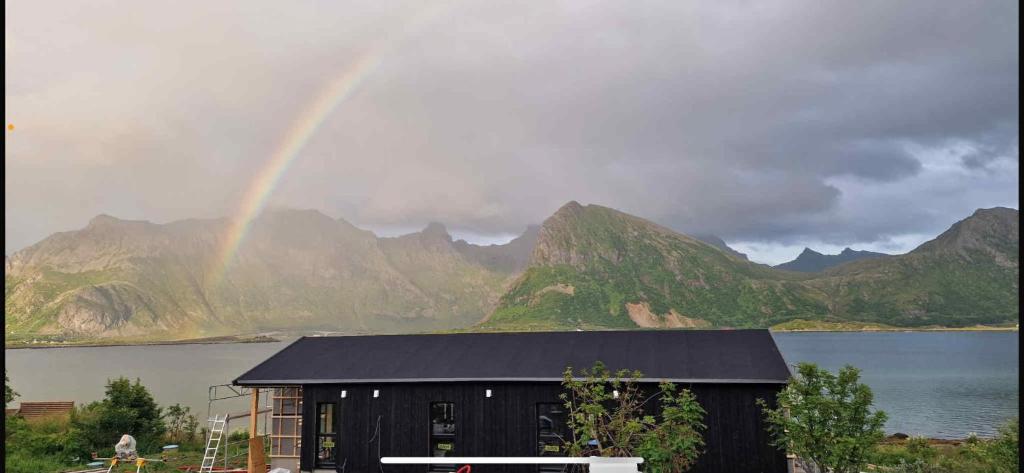 a rainbow over a house in front of a mountain at Fredvang Lodge, Lofoten in Hovdan