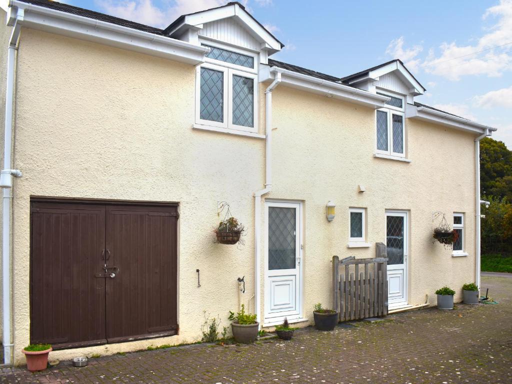 a white house with a brown garage at Orchardlea Apartment in Coldridge