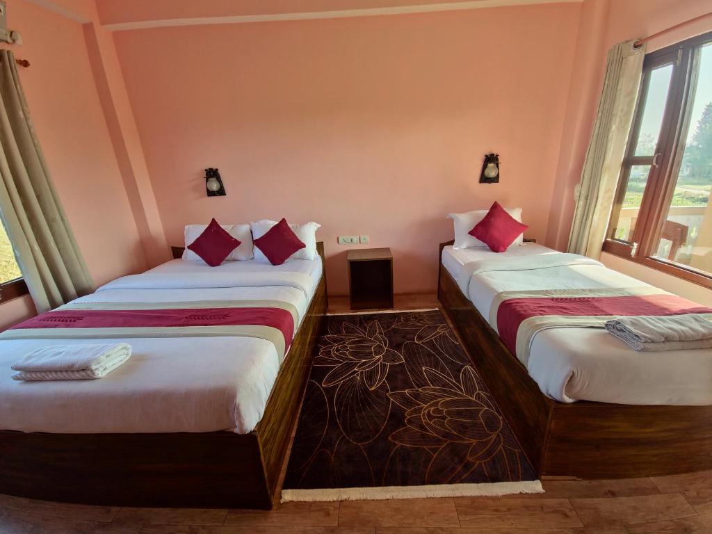 two beds in a room with two windows at Hotel Tree Tops in Sauraha