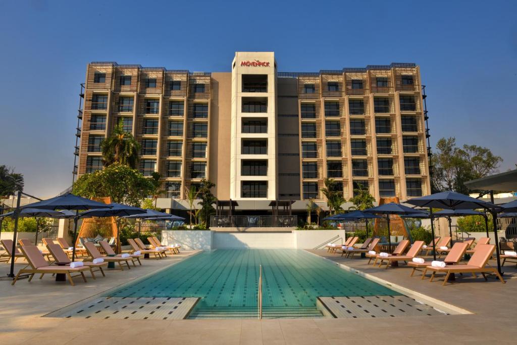 a hotel with chairs and a swimming pool in front of a building at Mövenpick Kigali in Kigali