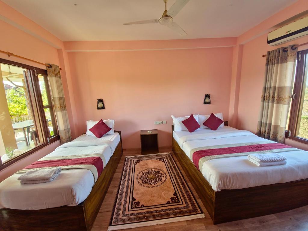 two beds in a room with two windows at Hotel Tree Tops in Sauraha