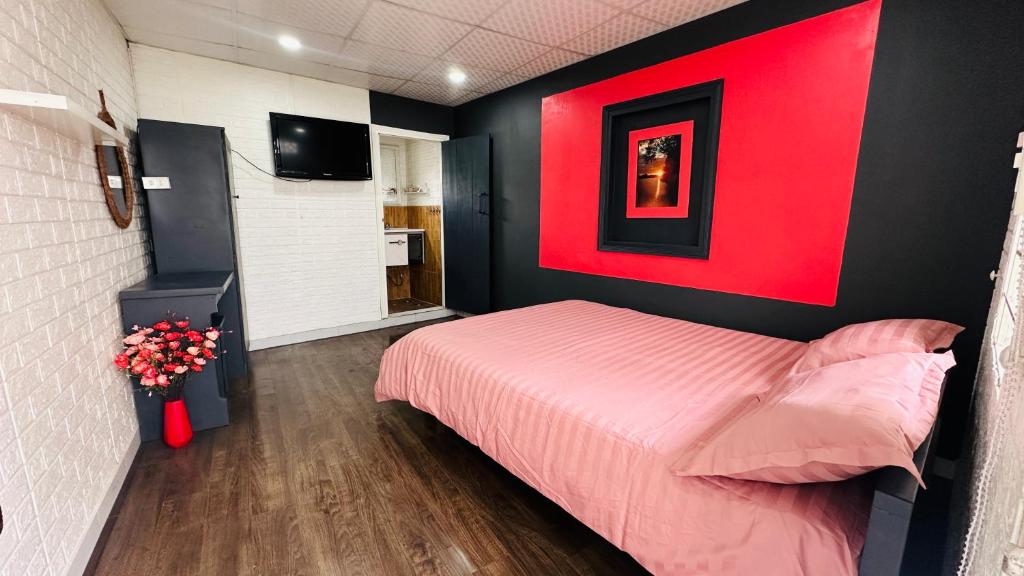 a bedroom with a pink bed and a red wall at Suri's House Homestay in Da Lat