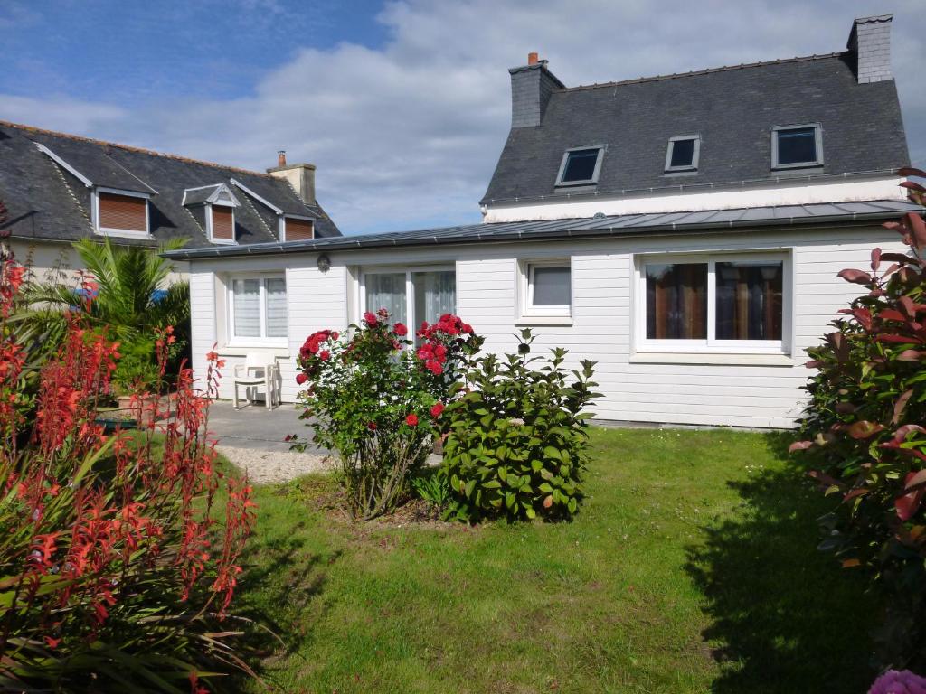 a white house with flowers in the yard at maison 6 personnes in Locquirec